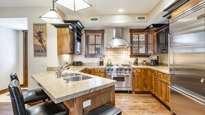 Una cocina moderna con encimeras de granito, electrodomésticos de acero inoxidable y armarios de madera.