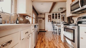 A kitchen with wooden flooring, white cabinets, a microwave, and an oven. - RIVER RETREAT, River Retreat, Fenced Backyard, Peaceful (River Falls)