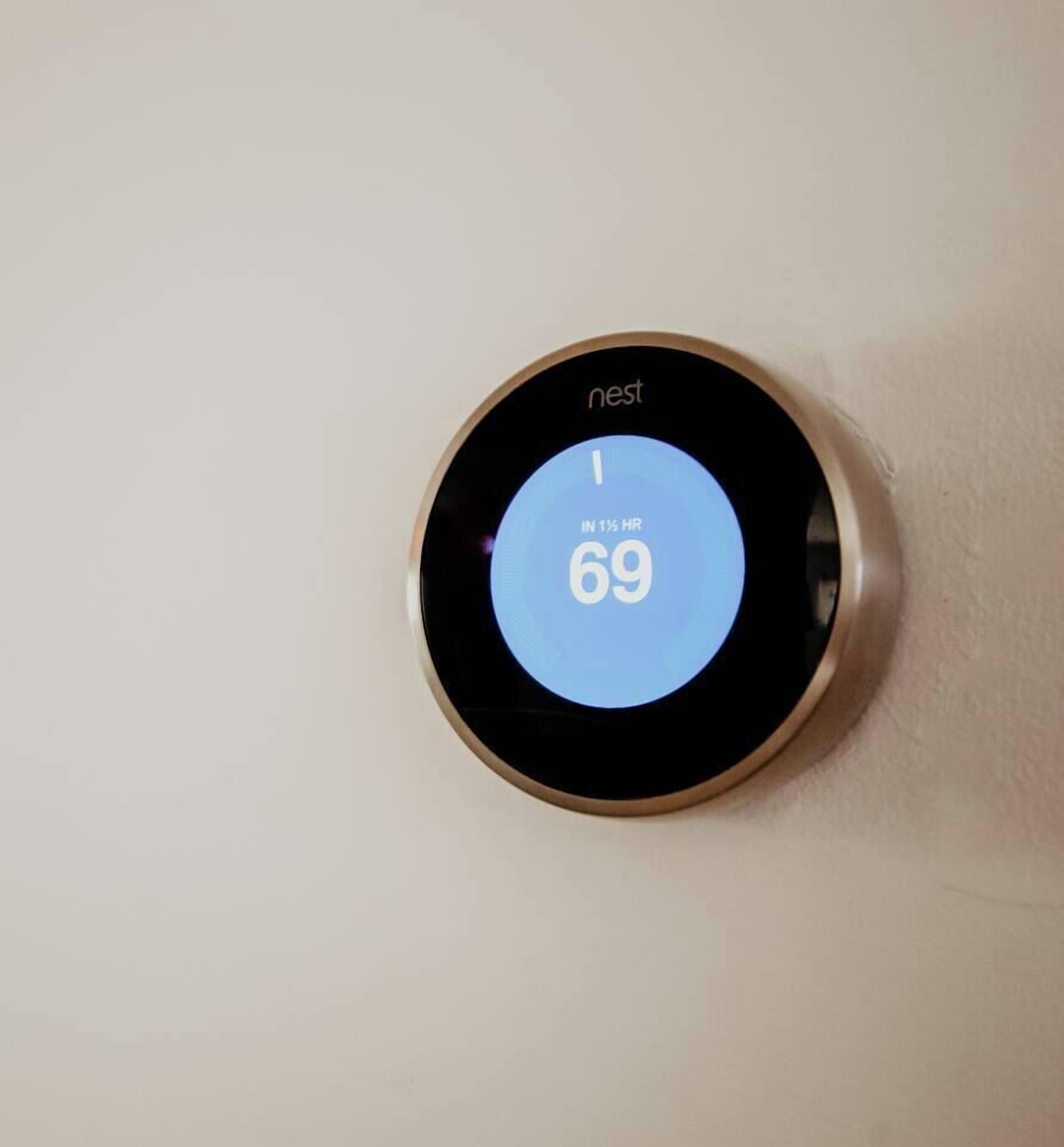 Termostato Nest montato su una parete che indica una temperatura di 21 gradi Celsius.
