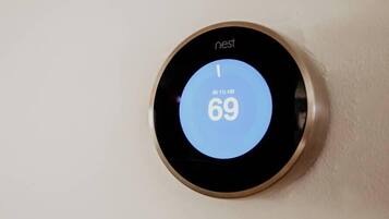 Termostato Nest montato su una parete che indica una temperatura di 21 gradi Celsius.