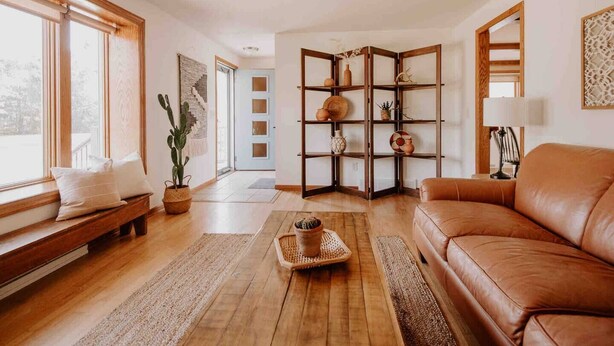 A cozy living room with a leather sofa, wooden floor, and a built-in bookshelf with decorative items. - RIVER RETREAT, River Retreat, Fenced Backyard, Peaceful (River Falls)