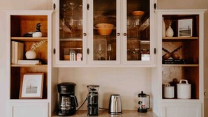 A kitchen with white cabinetry, a coffee maker, a kettle, and a French press. - RIVER RETREAT, River Retreat, Fenced Backyard, Peaceful (River Falls)