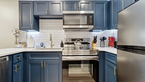 A modern kitchen with dark blue cabinets, stainless steel appliances, and a white tiled backsplash. - Quiet Mountain Home with Fireplace, A+ location! (Banner Elk)