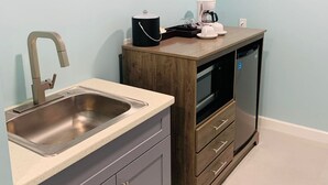 A compact kitchen with a sink, a coffee maker, and a microwave. - The New View Inn (Road Town)