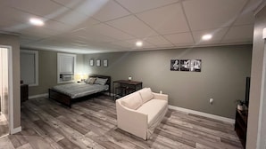 A bedroom with a bed, a nightstand, a desk, a chair, and a couch. - The Studio Above the Studio (Jackson)