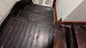 A wooden staircase with a dark finish leading to a room with a white door and a tiled floor. - The Studio Above the Studio (Jackson)