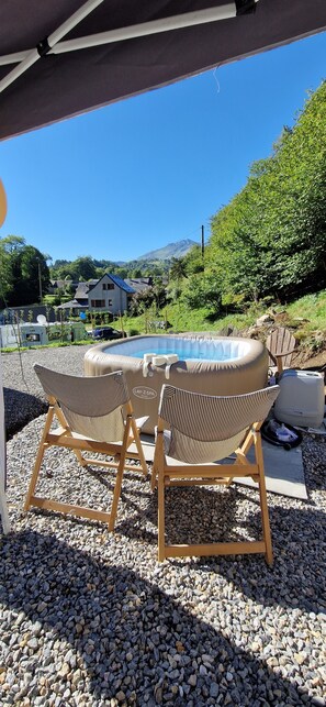 A pool area with two lounge chairs and a covered seating area.
