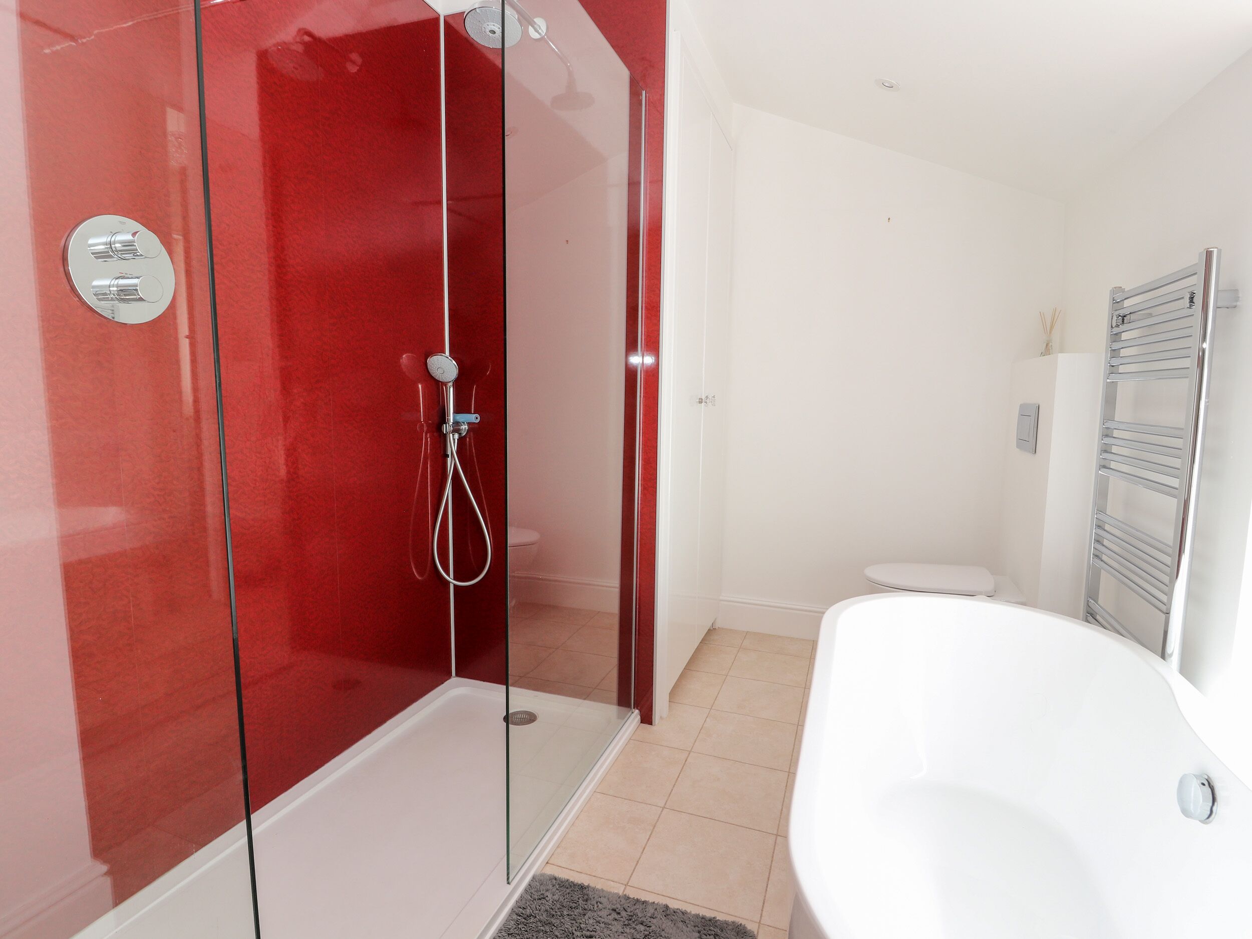 Un baño moderno con cabina de ducha de vidrio, una bañera blanca y un inodoro.