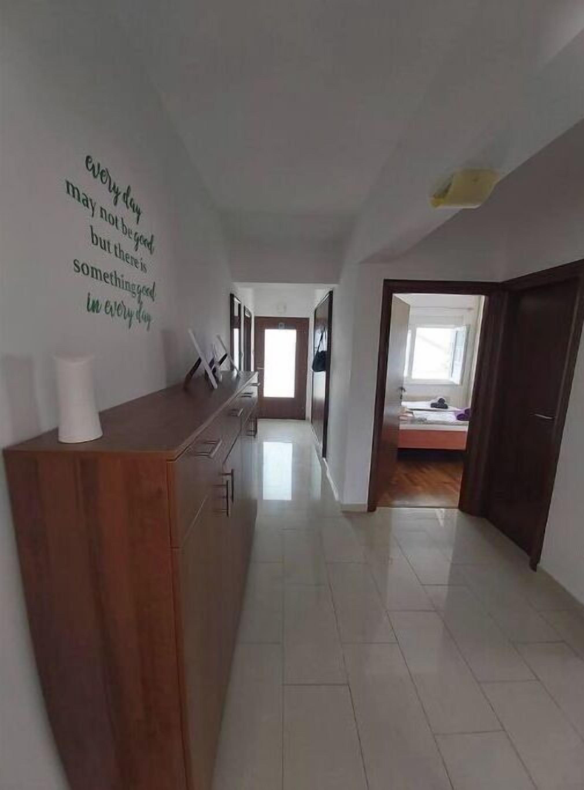 A hallway with a wooden counter, a wall with motivational text, and a bed in the background.