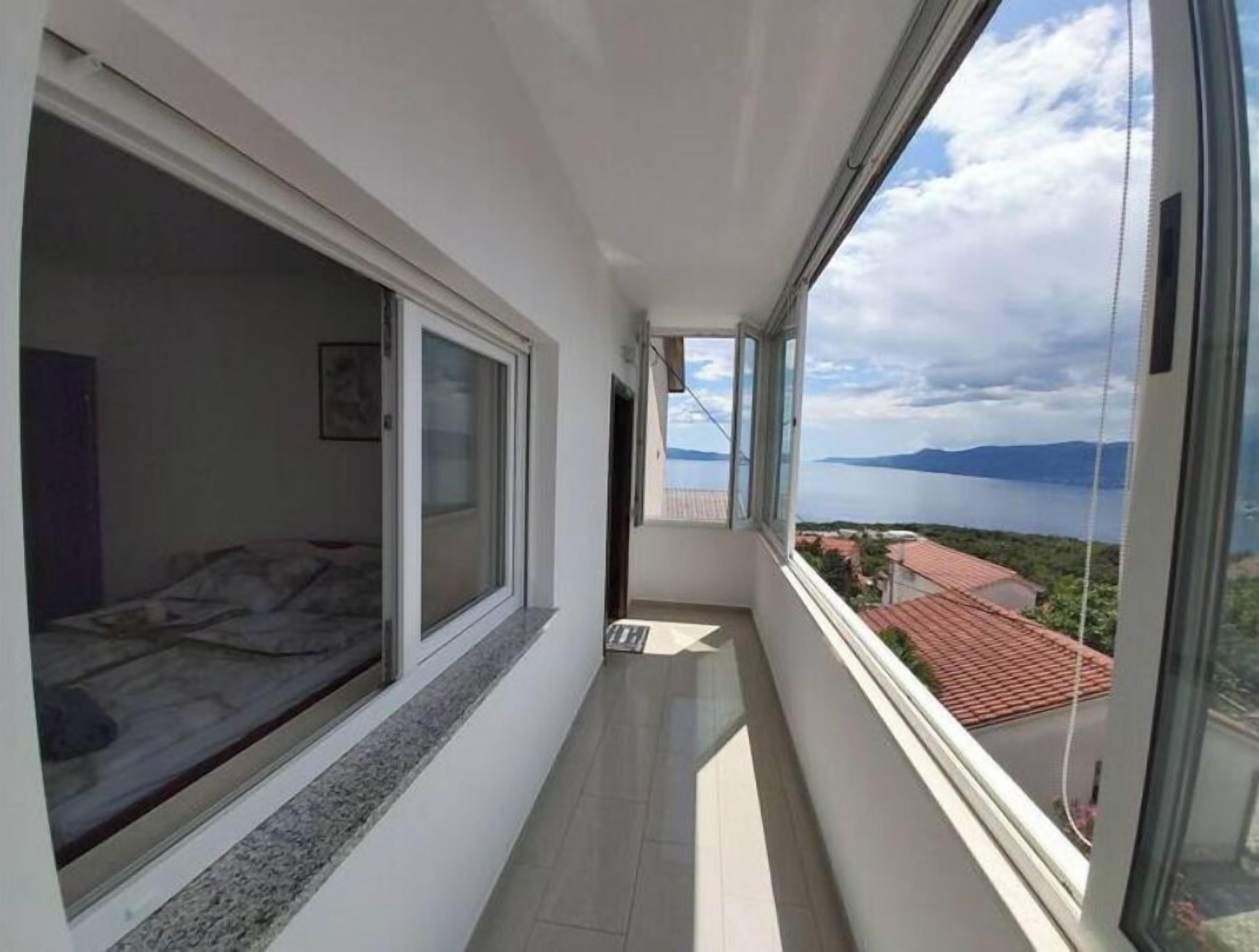 A narrow balcony with a view of a lake and mountains.