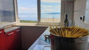 A kitchen with a view of the sea, a pot of uncooked pasta, and a bottle of olive oil on the counter. - A dreamlike view & private parking in Kastav, Apartment Alina (Kastav)