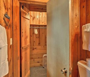 A wooden bathroom with a shower, a towel rack, and a toilet.