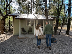 A small building with a porch, two chairs, and a gravel ground.