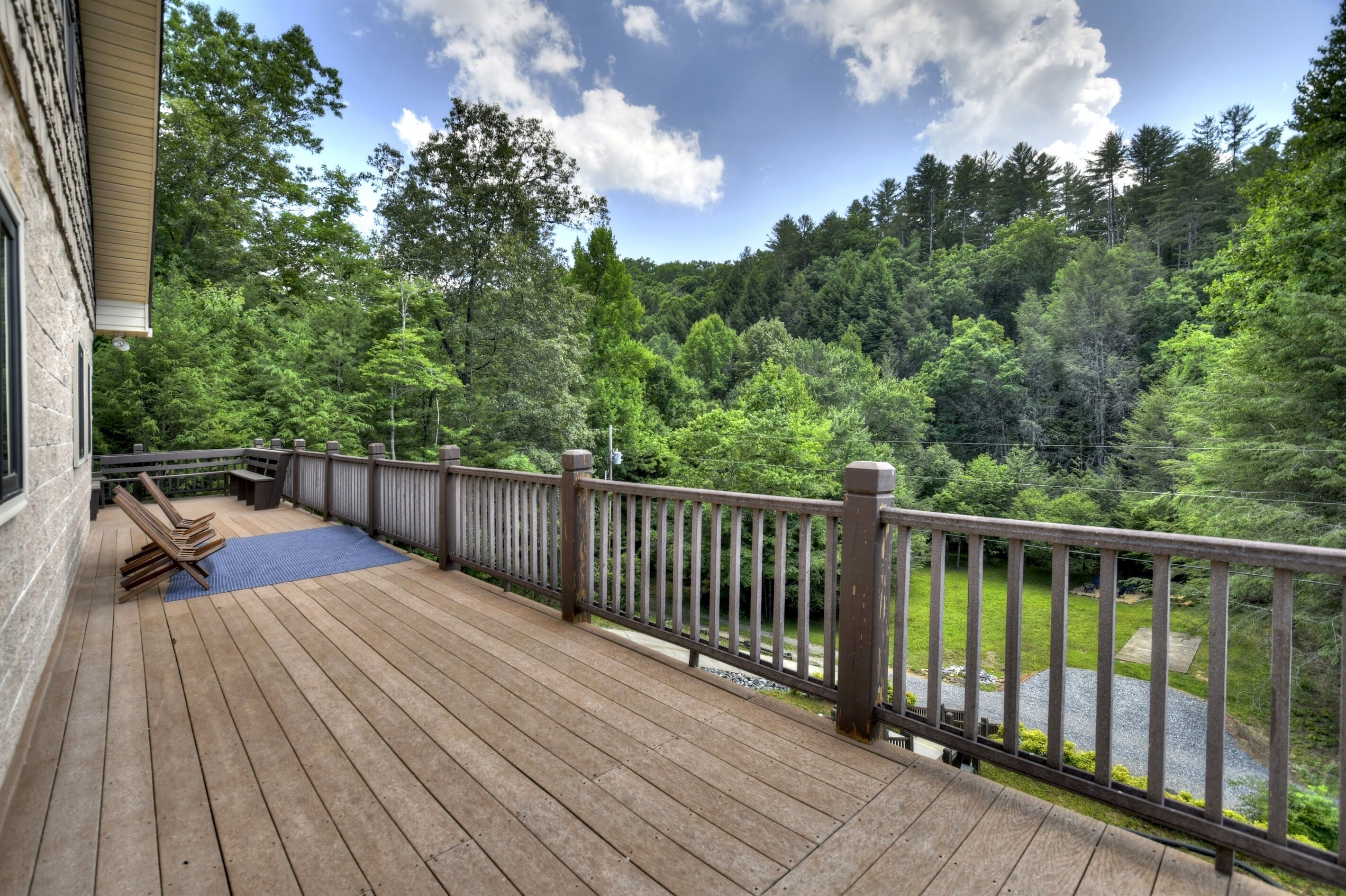 A wooden deck with a railing overlooking a forested area.