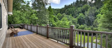 A wooden deck with a railing overlooking a forested area.