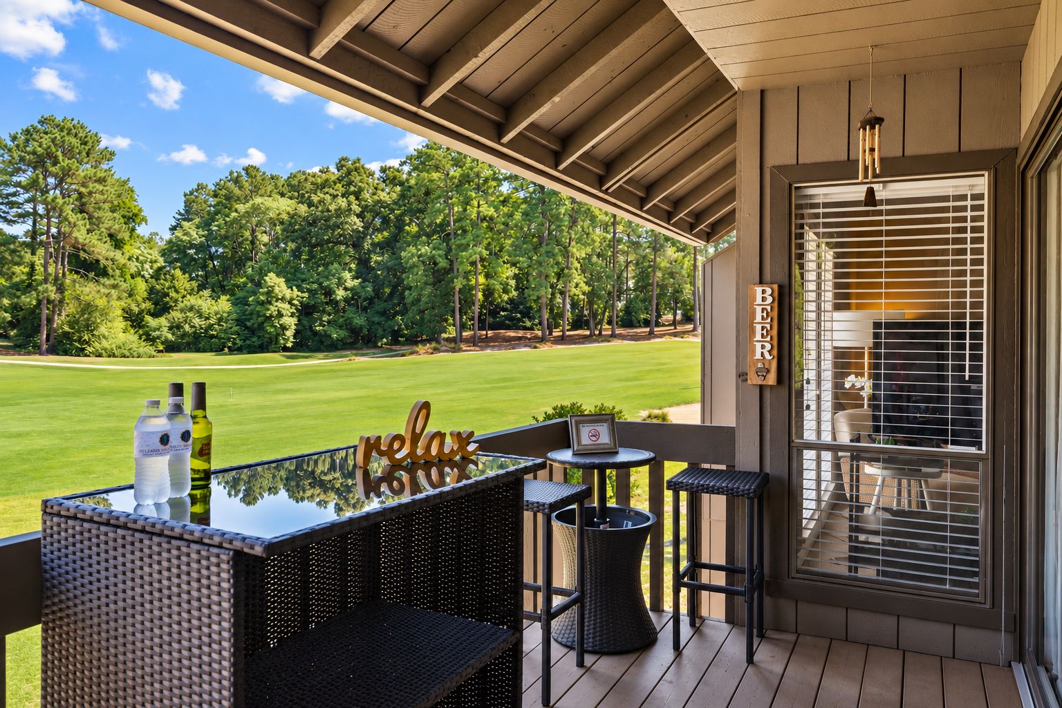 A covered outdoor seating area with a view of a golf course, a sign reading 'BEER', and a 'relax' sign.