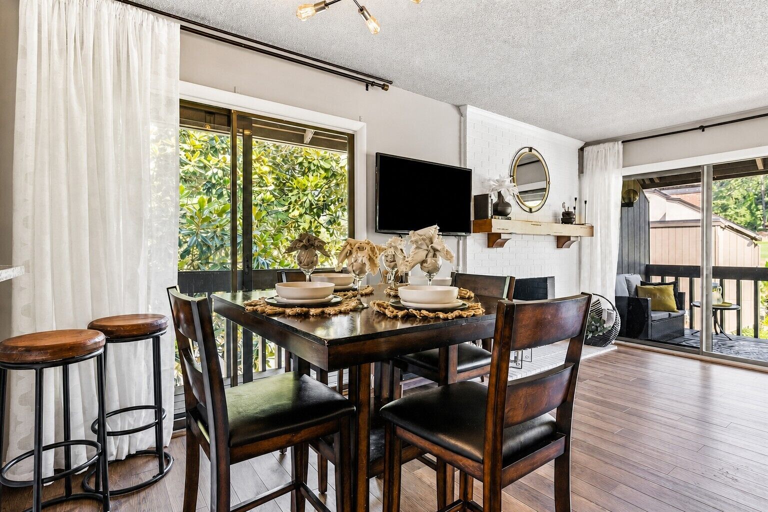 A dining area with a wooden table, chairs, and a TV mounted on the wall.