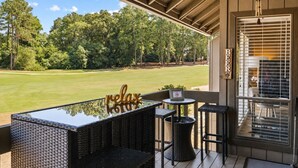A covered outdoor seating area with a view of a golf course, a sign that says 'BEER', and a 'relax' sign on a table. - Legends & Masters | Walk to Pinehurst Clubhouse | Hallmark-Style Charm (Pinehurst)