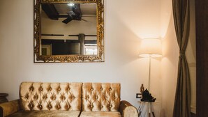 A room with a tufted sofa, a large ornate mirror, a standing lamp, and a ceiling fan. - SD-1 HABITACION EN LA CIUDAD ANTIGUA (Cartagena)