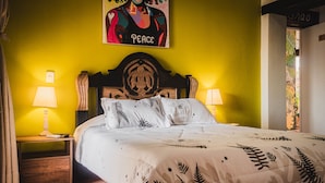 A bed with a patterned bedspread, a wooden headboard, two bedside lamps, and a wall with a 'Peace' poster. - SD-1 HABITACION EN LA CIUDAD ANTIGUA (Cartagena)