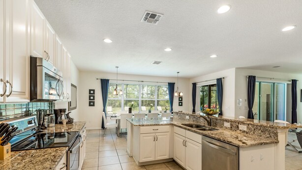 A modern kitchen with granite countertops, stainless steel appliances, and a central island. - Contemporary 6 Bed 6 Bath Luxury Villa at Watersong (Davenport)