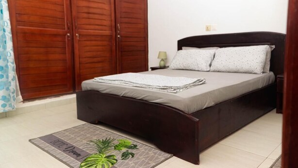 Un dormitorio con cama, armario de madera y una mesita de noche con lámpara.