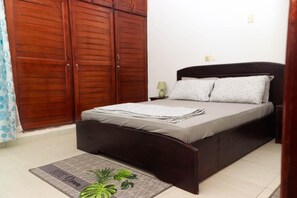 Un dormitorio con cama, armario de madera y una mesita de noche con lámpara.