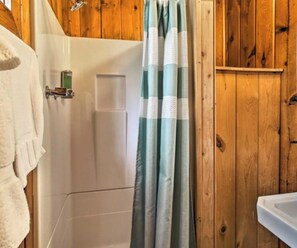 Ein Badezimmer mit Dusche, Handtuchhalter und Holzwänden.