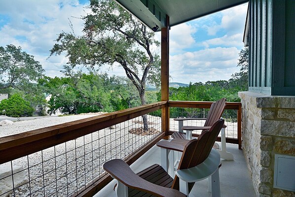 A balcony with a view of trees and a stone wall.