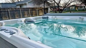 Un jacuzzi en un patio trasero con una valla de madera y casas al fondo.
