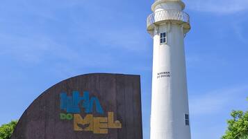 Ein Leuchtturm mit einem Schild, auf dem 'Marina do Brasil' steht, und einem weiteren Schild mit der Aufschrift 'Charme, Aventura e Natureza'.