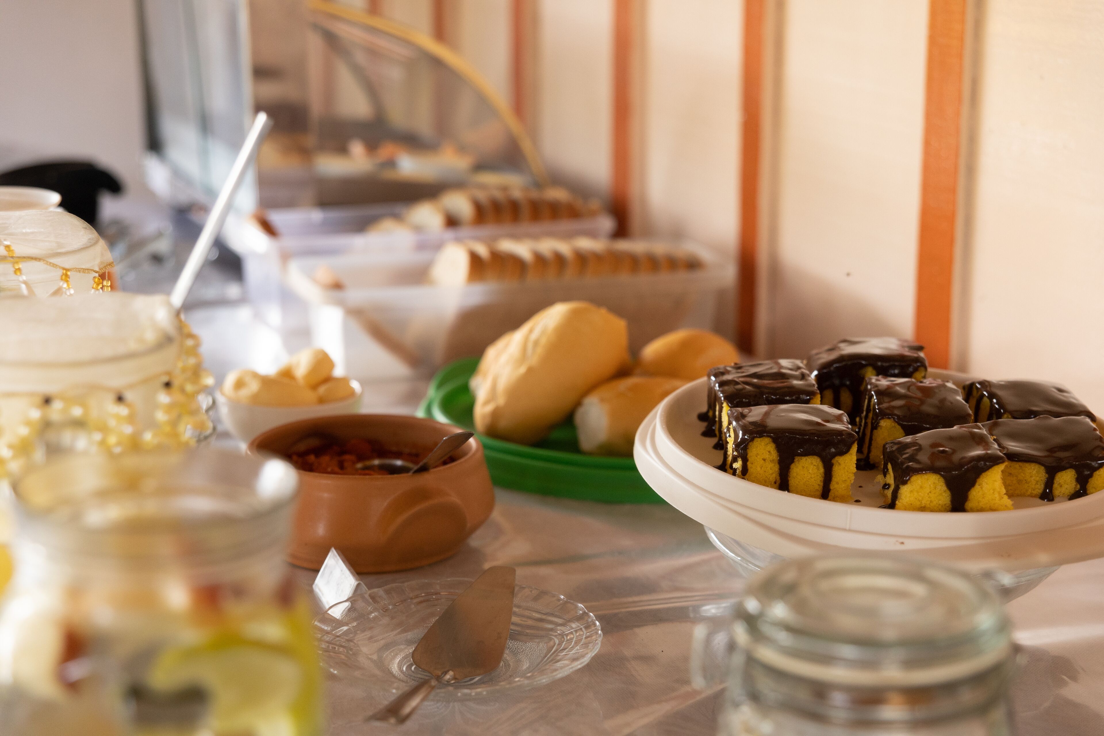 Un tavolo da buffet con diversi cibi, tra cui torte, pasticcini e una ciotola di salse.