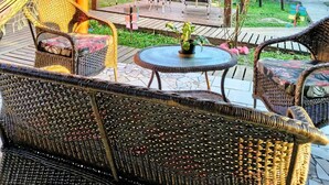 Un espacio al aire libre techado con mobiliario de mimbre, una hamaca y una pérgola.