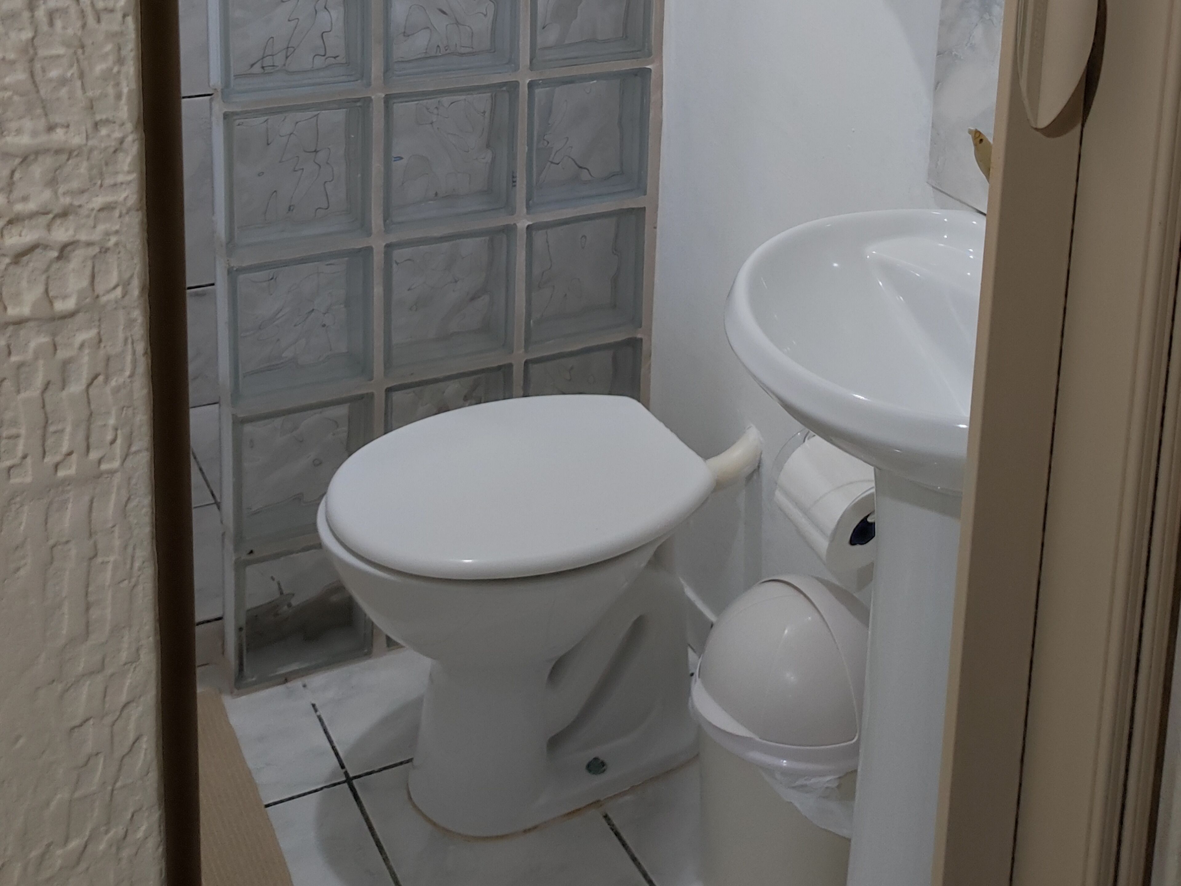 A bathroom with a toilet, sink, and a tiled shower area.