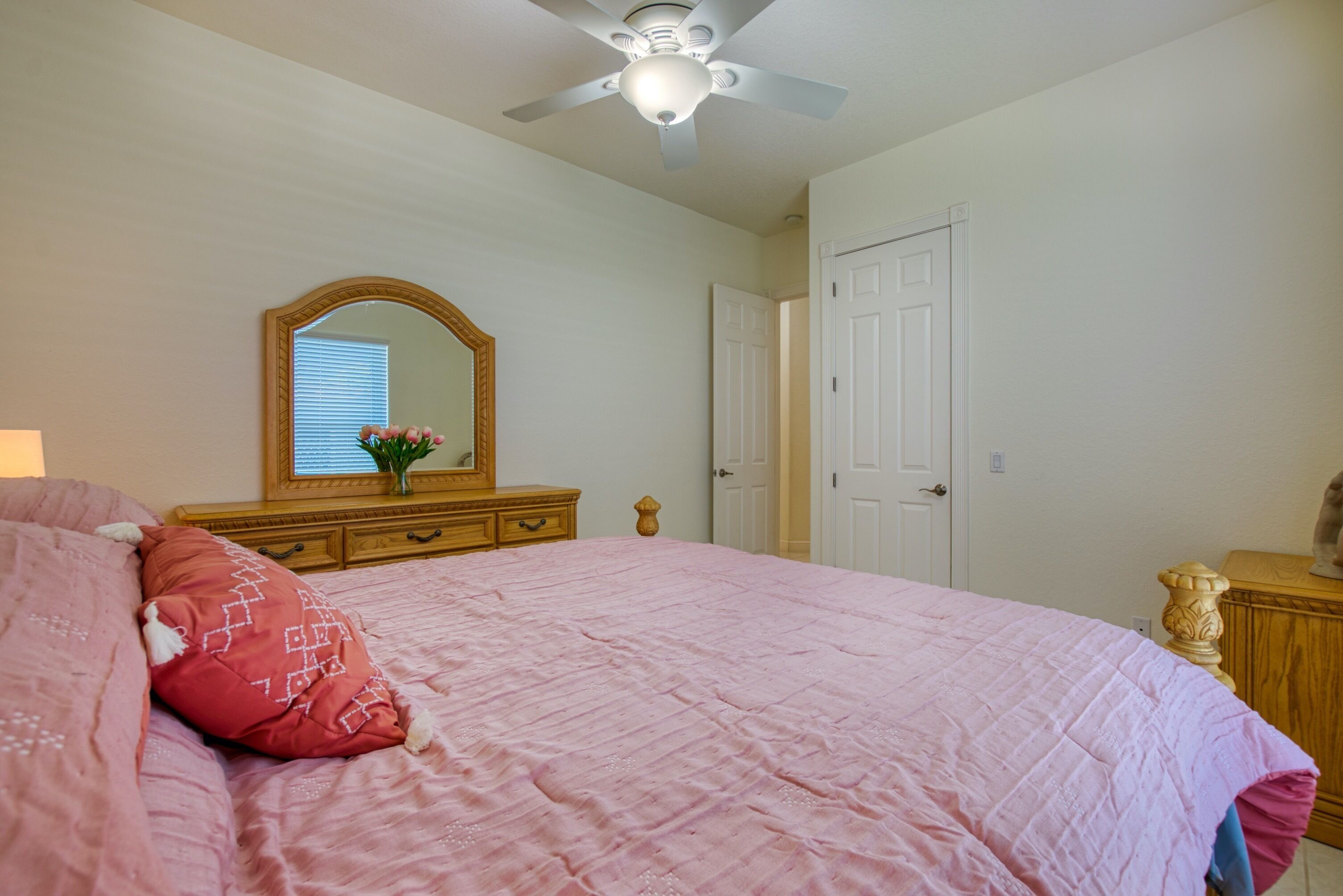 Un dormitorio con cama, cómoda, espejo y ventilador de techo.