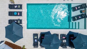 An aerial view of a swimming pool with lounge chairs and umbrellas.