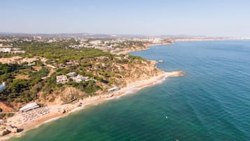 Une vue aérienne d’une zone côtière avec une plage, des bâtiments et un ciel dégagé.