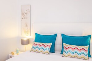 Ein Bett mit zwei Kissen, ein Nachttisch mit Lampe und ein Wandbild.