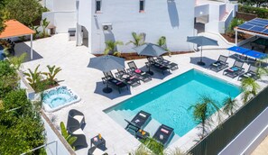 Een dakzwembad met ligbedden, een jacuzzi en een tafel met parasols.