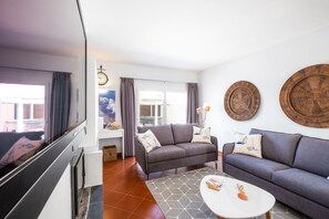 Een moderne woonkamer met een grijze bank, een witte salontafel en een televisie.