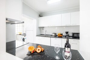 A modern kitchen with white cabinets, a black countertop, a dishwasher, a coffee maker, and a bottle of wine. - Modern villa w/ heatable pool & BBQ, Albufeira (Albufeira)