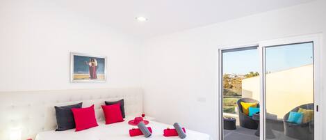 Une chambre avec un grand lit, une table de chevet, une fenêtre et une vue sur l’extérieur.