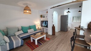 Un salon moderne avec un canapé, un téléviseur et un coin repas.