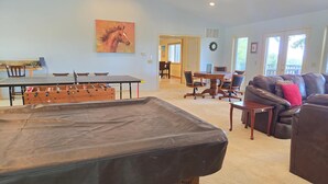 A living room with a foosball table, leather sofa, and a dining area with a round table and chairs. - KINGSVIEW -Magnificent Private Lakefront Retreat with Breathtaking Views. (Garfield)
