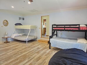 Een kamer met twee stapelbedden, een klein tafeltje met een ventilator en een houten vloer.