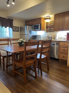 A kitchen with wooden cabinets, a stainless steel refrigerator, a microwave, a toaster, and a dishwasher.
