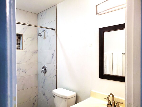 A bathroom with a shower, toilet, and sink.