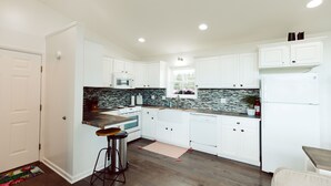 A modern kitchen with white cabinets, a black countertop, and a stainless steel range hood. - King Bed, Zero Entry, Close to Town (Sault Ste. Marie)
