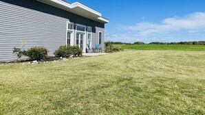 A modern house with a large lawn and a clear blue sky. - King Bed, Zero Entry, Close to Town (Sault Ste. Marie)