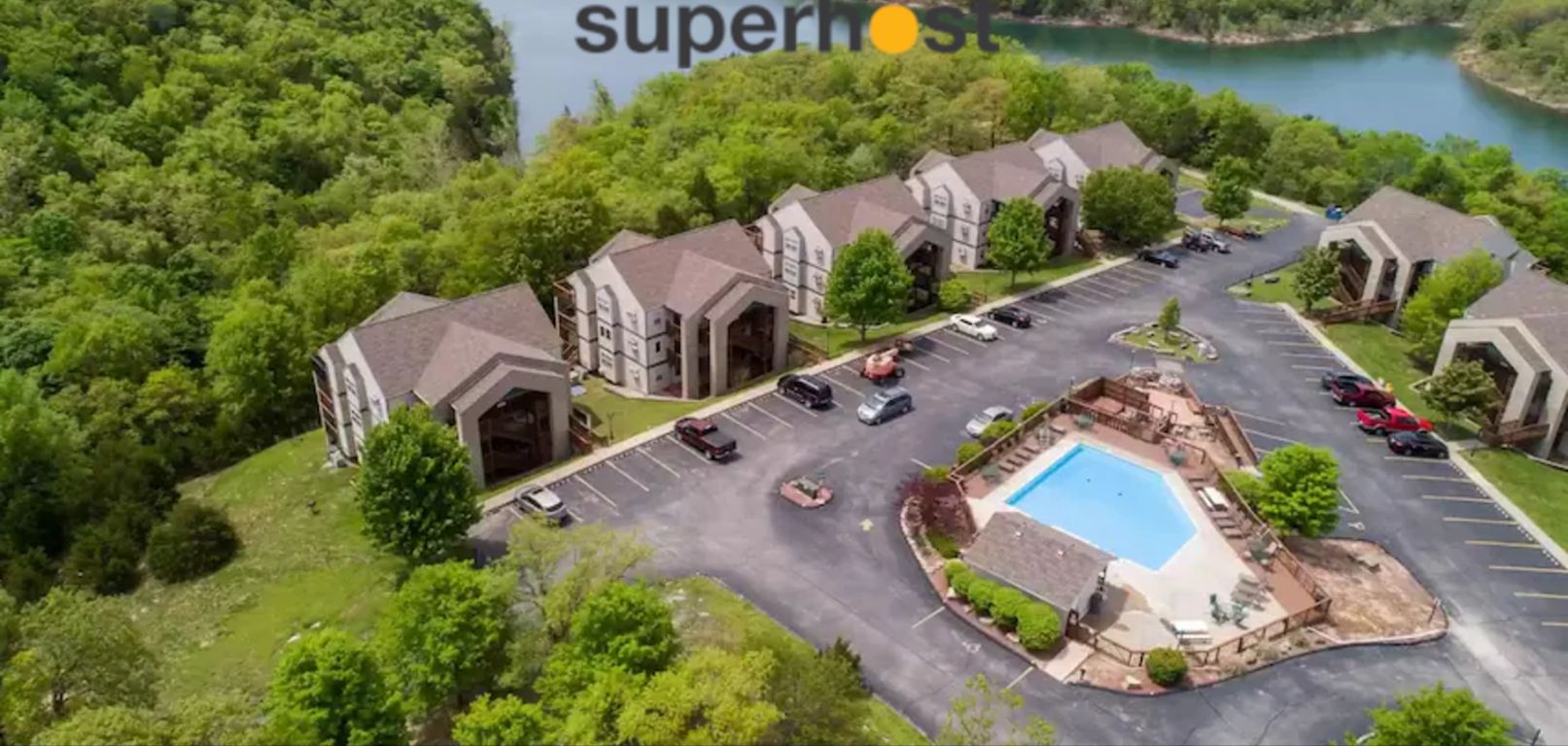 An aerial view of a resort with multiple buildings, a swimming pool, and a parking lot.